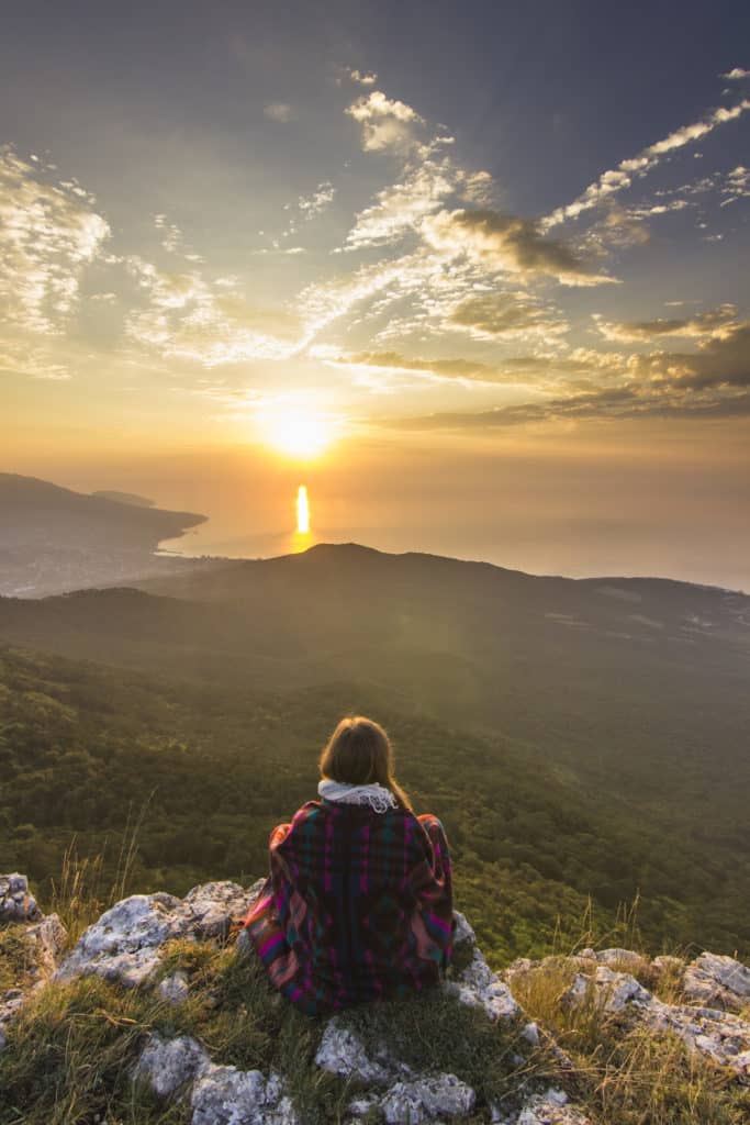 sitting girl in yellow sunrise in mountains above sea sitting girl in yellow sunrise in mountains above sea